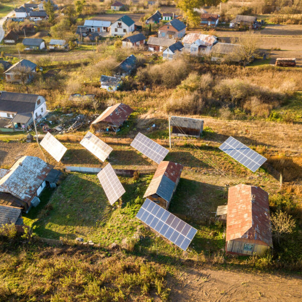 Aerial top down view of solar photo voltaic panels in green rural area. Clean renewable energy in private village environment.