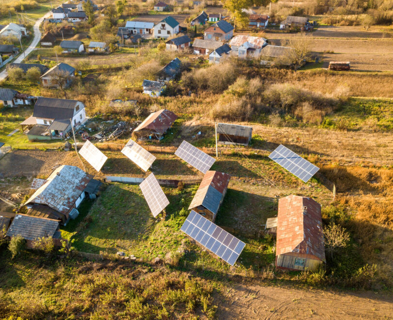 Aerial top down view of solar photo voltaic panels in green rural area. Clean renewable energy in private village environment.